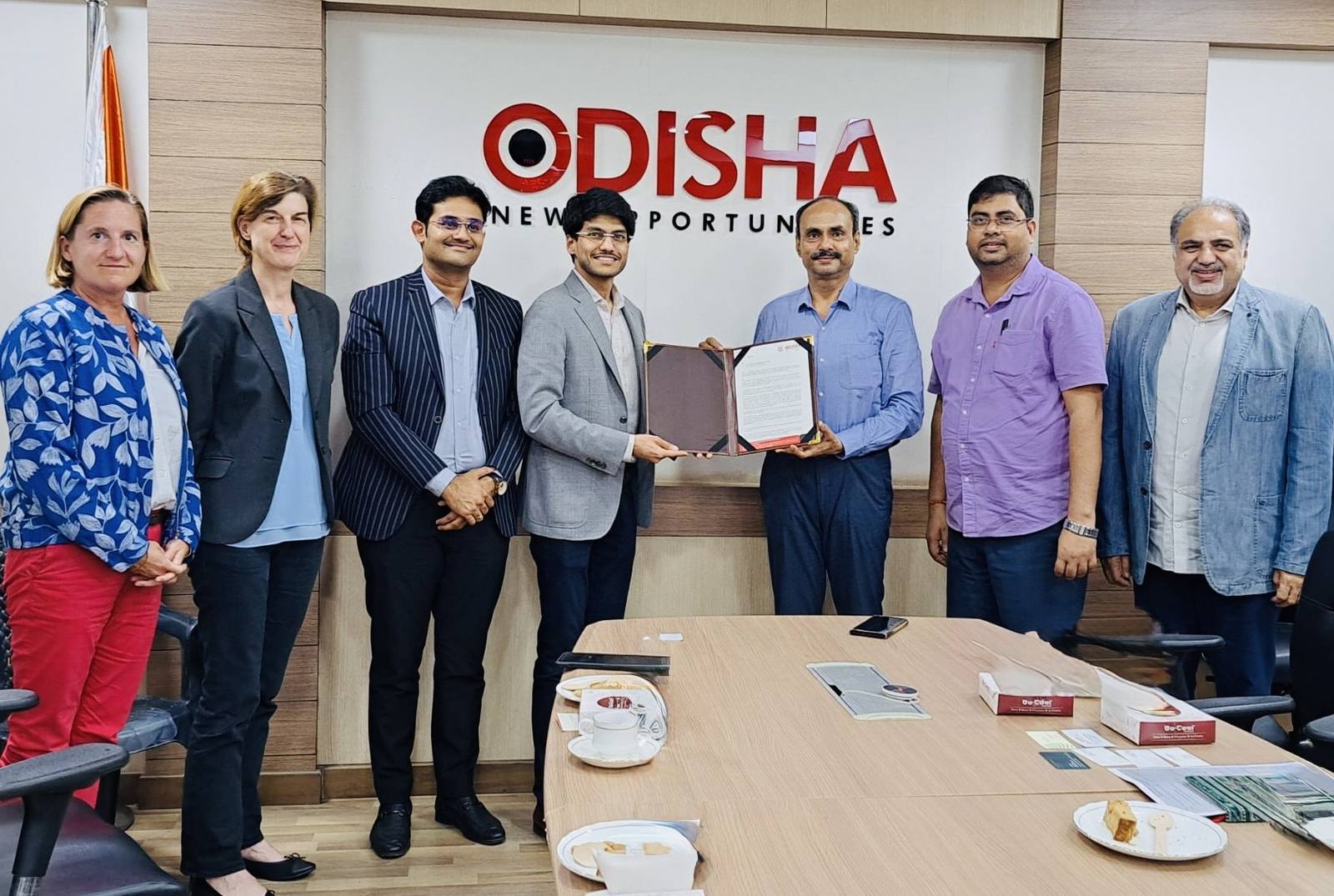 Project representatives presenting a framed document at an Odisha investment engagement