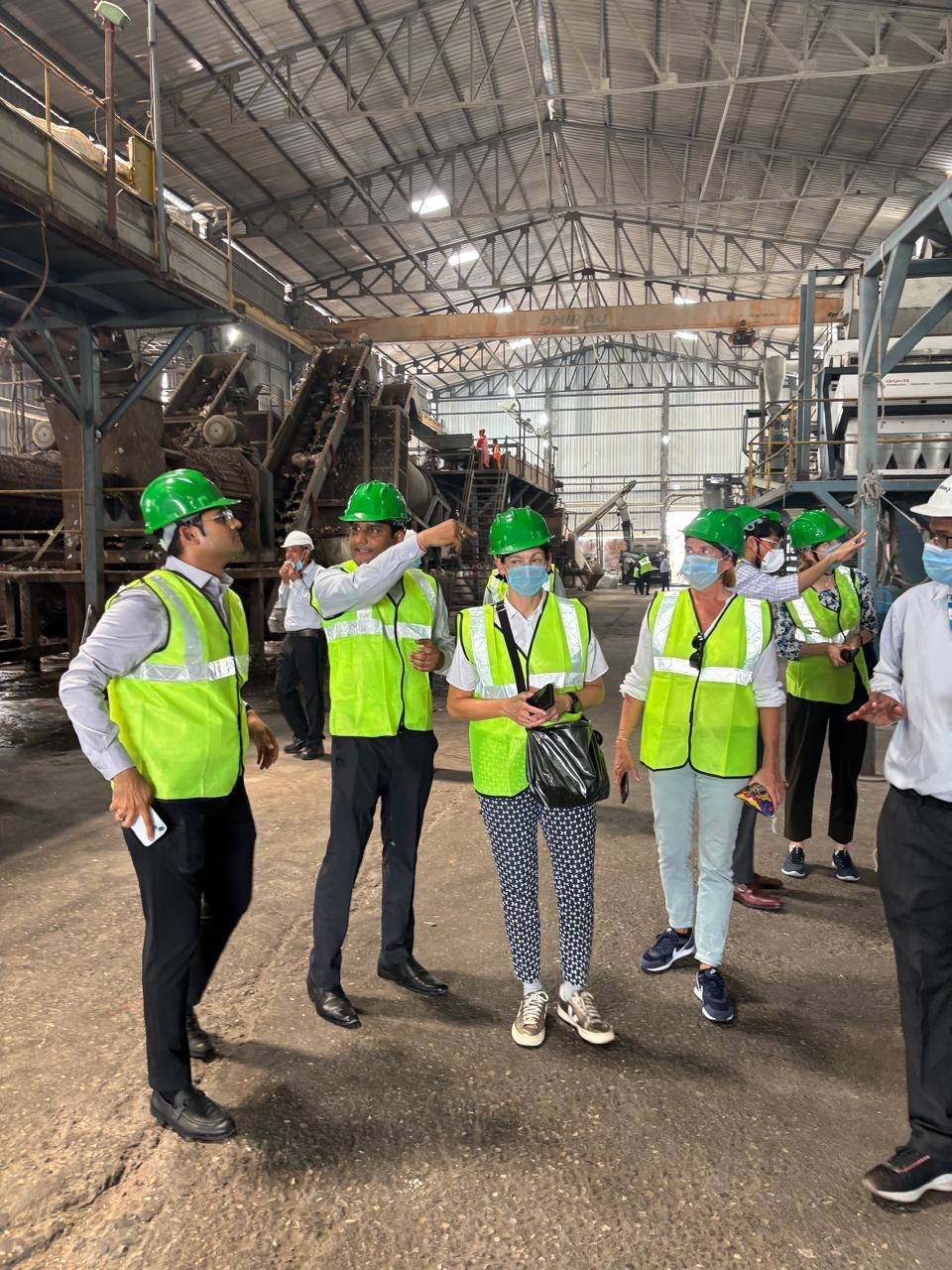Visitors and workers inspecting recycling machinery inside an operating facility